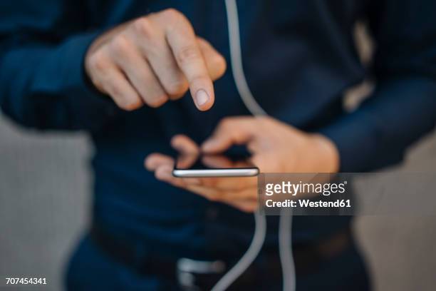 businessman using smartphone with connected earphones - button down shirt close up stock pictures, royalty-free photos & images