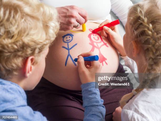 children painting on pregnant mother's belly - family with two children stock pictures, royalty-free photos & images