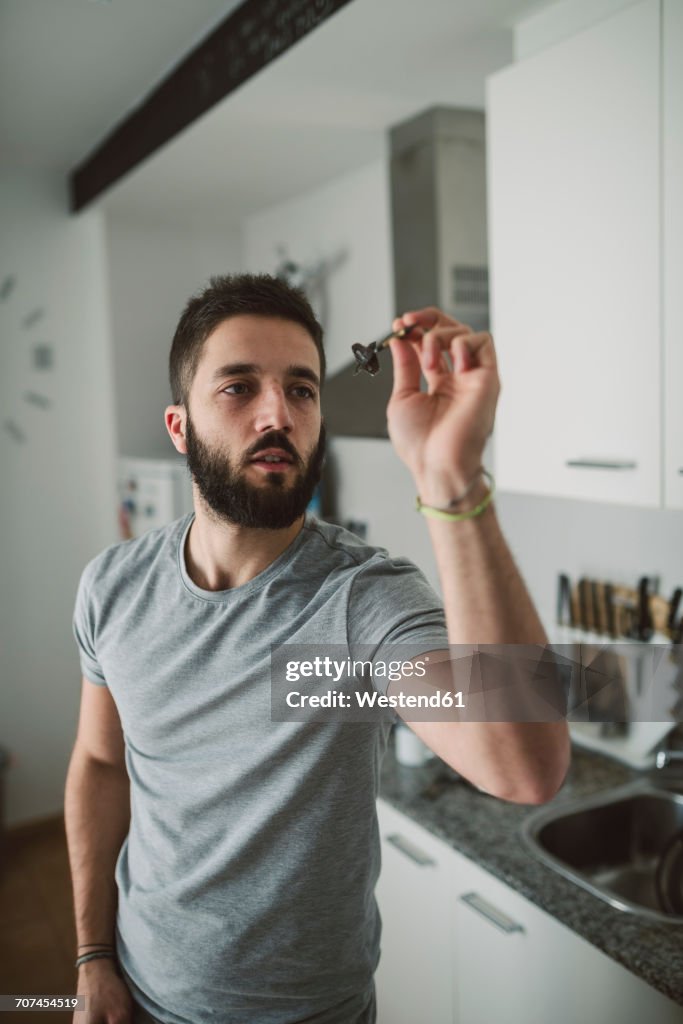Young man playing darts in his kitchen