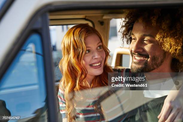 smiling young woman looking at boyfriend in a car - person gemischter abstammung stock-fotos und bilder