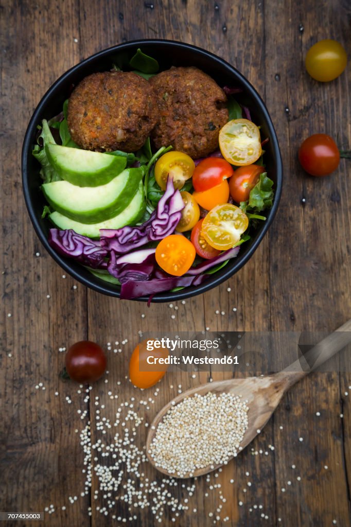 Lunch bowl of leaf salad, red cabbage, avocado, tomatoes and quinoa fritters