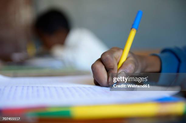 madagascar, fianarantsoa, schoolboy writing in notebook - madagascar stock-fotos und bilder