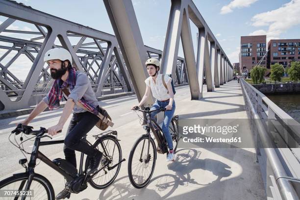 germany, hamburg, couple riding electric bicycles on a bridge - e bike stock-fotos und bilder