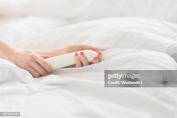 hand of woman holding sex toy in bed - comportamento sessuale umano foto e immagini stock