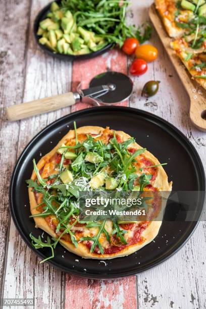 vegetarian pizza with avocado, rocket, tomatoes and parmesan on plate - roquette photos et images de collection