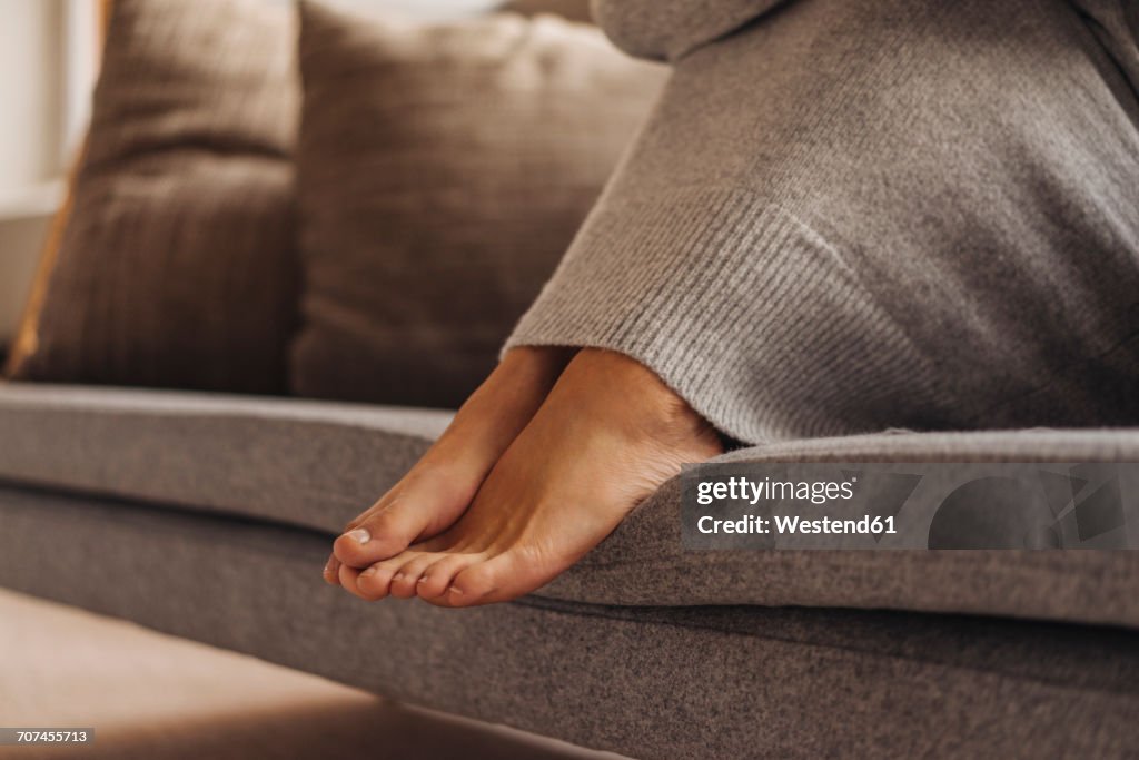 Close-up of woman's feet sitting on couch