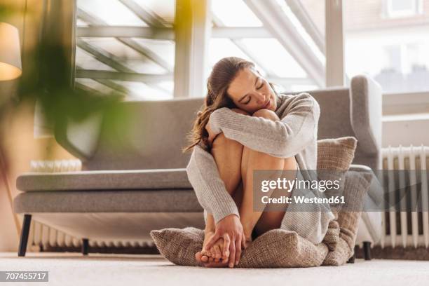 woman with closed eyes sitting on cushion on floor - piernas de mujer fotografías e imágenes de stock