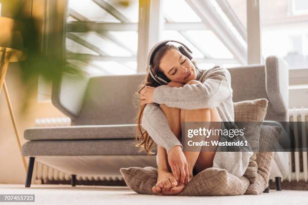 woman with closed eyes sitting on cushion on floor wearing headphones - beautiful long legs stock pictures, royalty-free photos & images