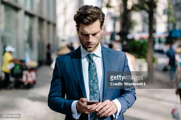 handsome businessman walking in manhattan, using mobile phone - cravate seule photos et images de collection