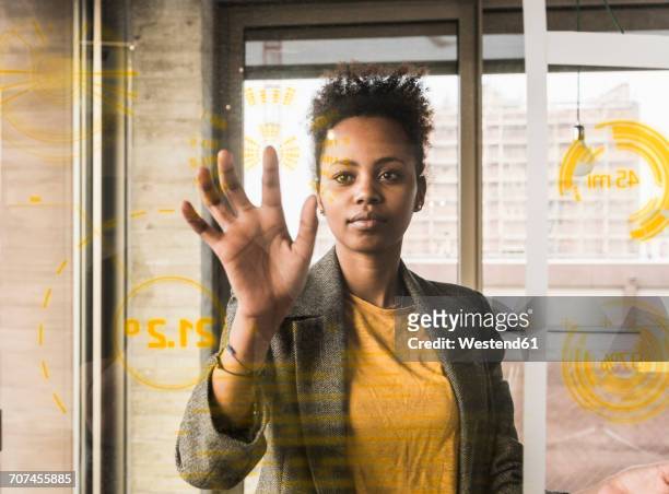 Young woman touching glass wall with data in office