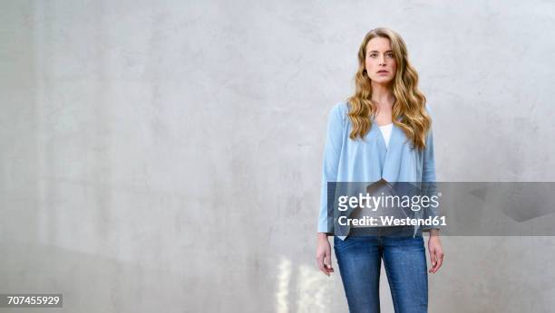 portrait of serious blond woman in front of grey wall - delusione foto e immagini stock