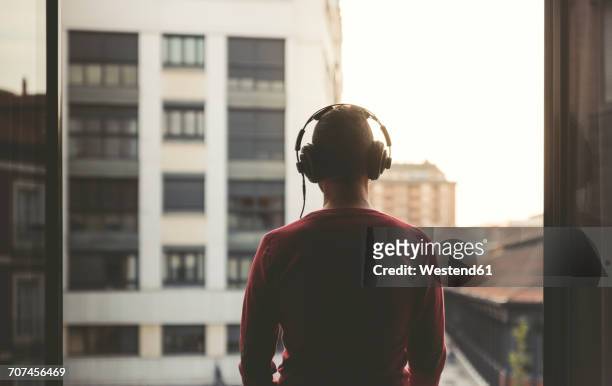 man wearing headphones on a balcony in the city at sunset - listening imagens e fotografias de stock
