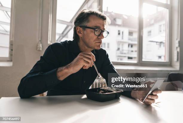 mature businessman checking cell phone during lunch break in office - ready meal photos et images de collection