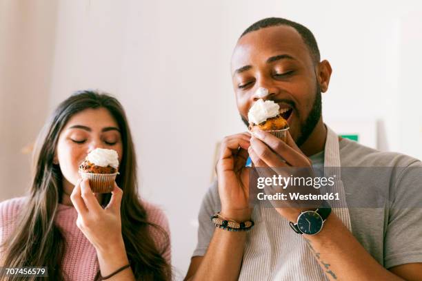 young couple having fun, eating fresh cupcakes - cupcake stock-fotos und bilder