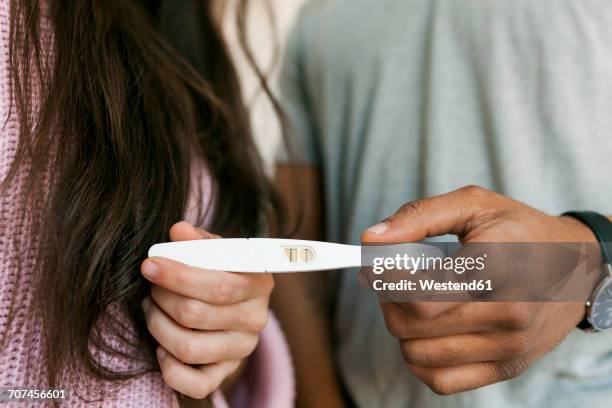 young couple holding positive pregnancy test - zwangerschapstest stockfoto's en -beelden