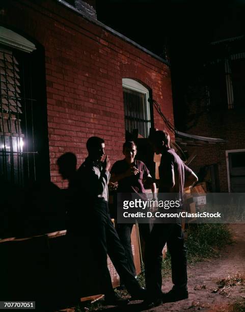 1960s THREE BOYS LOITERING ALLEY NIGHT SMOKING CIGARETTES CRIME