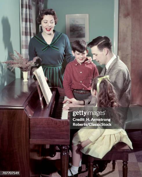 1950s FAMILY MAN FATHER PLAYING PIANO MOTHER WOMAN BOY GIRL SON DAUGHTER SINGING ALONG TOGETHER IN LIVING ROOM