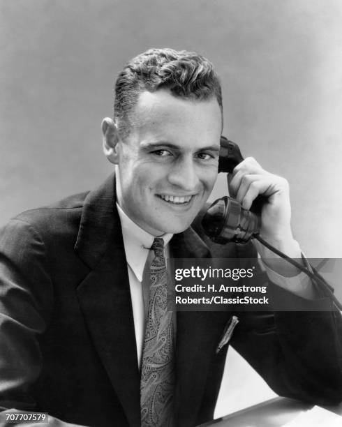 1930s MAN TALKING ON TELEPHONE LOOKING AT CAMERA