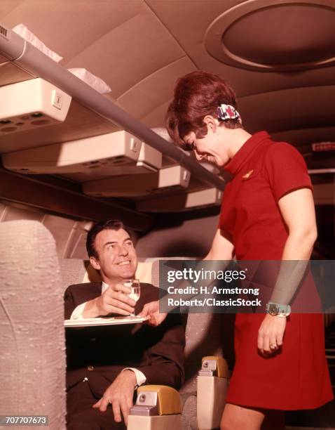 1960s 1970s AIRPLANE PLANE STEWARDESS SERVING BUSINESS MAN DRINK WINE WOMAN COMMERCIAL AIR TRAVEL