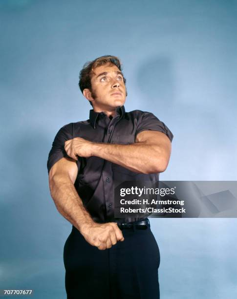 1970s MUSCULAR YOUNG MAN ROLLING UP SHIRT SLEEVE SYMBOLIC READY TO WORK INTENT DETERMINED