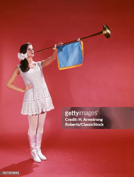 1960s WOMAN WEARING CROCHETED MINISKIRT BLOWING A HERALDING TRUMPET