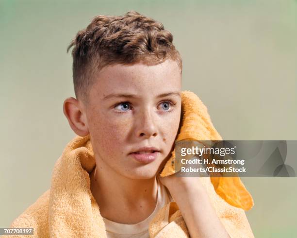 1960s ADOLESCENT YOUTHFUL BOY WITH BLUE EYES CURLY HAIR AND FRECKLES WASHING FACE WITH WASH CLOTH AND TOWEL
