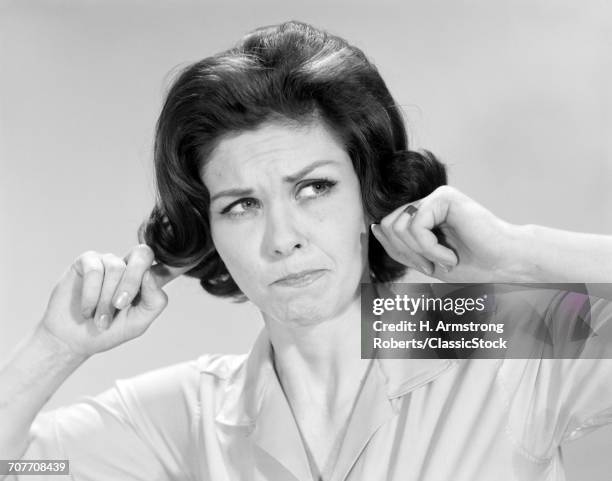 1960s BRUNETTE WOMAN STICKING FINGERS INTO HER EARS