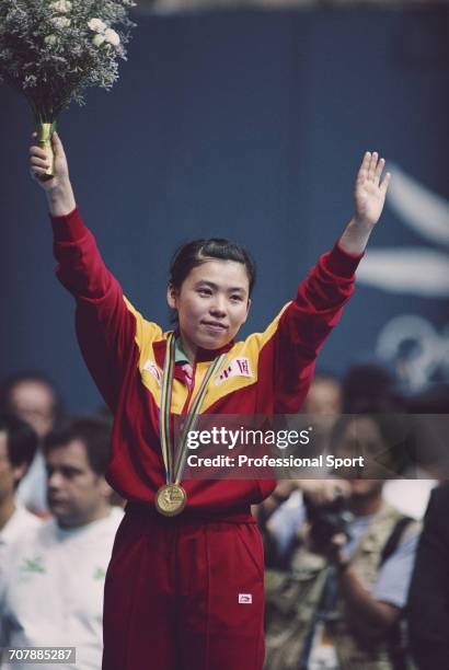 Chinese table tennis player Deng Yaping raises her arms in the air on the medal podium after competing for China to win the gold medal in the Women's...