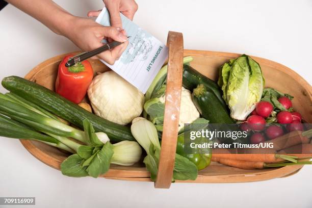 garden trug with a selection of fresh produce womans hand holding shopping list - トラッグ ストックフォトと画像