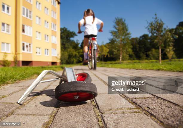 girl on bicycle leaving her training wheels behind - training wheels stock pictures, royalty-free photos & images