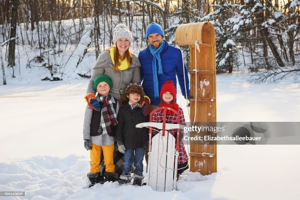 Portrait of a family standing in snow with a sledge