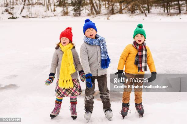 three children on ice skates singing carols - christmas carols stock-fotos und bilder