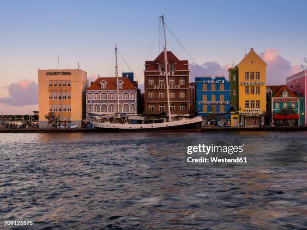 curacao, willemstad, schooner and colorful houses at waterfront promenade - willemstad stock pictures, royalty-free photos & images