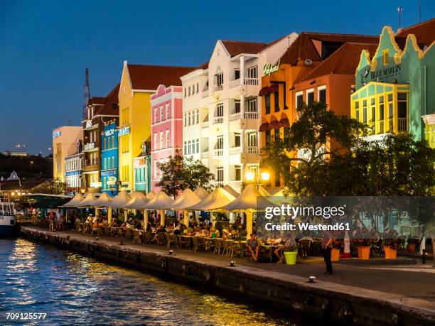 curacao, willemstad, punda, colorful houses at waterfront promenade in the evening - curaçao stockfoto's en -beelden