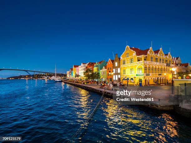 curacao, willemstad, punda, colorful houses at waterfront promenade in the evening - curacao stock pictures, royalty-free photos & images