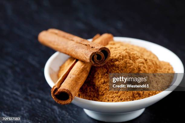 bowl of cinnamon powder and two cinnamon sticks - cinnamon stock pictures, royalty-free photos & images