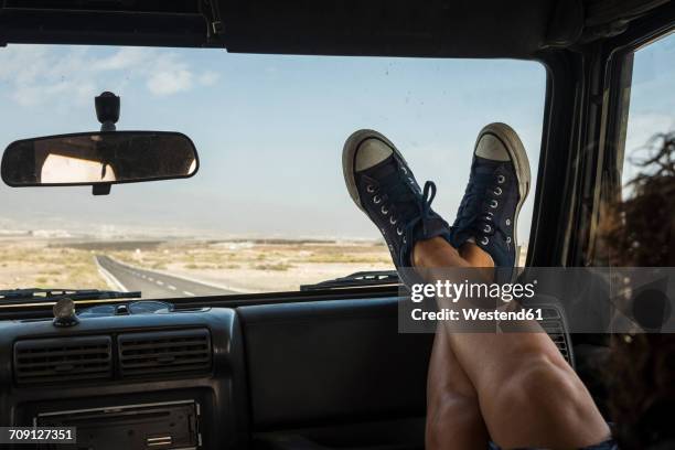 woman sitting in car with feet up on dashboard - running shoes sky stock-fotos und bilder