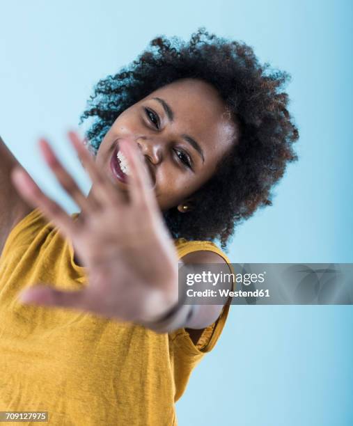 portrait of smiling young woman raising her hand - geste stop photos et images de collection