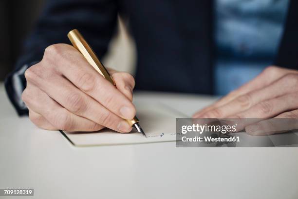 hand of businessman writing with golden fountain pen, close-up - escritores fotografías e imágenes de stock