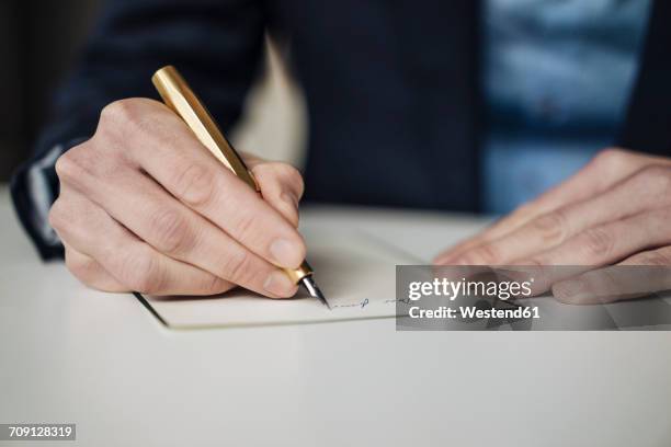 hand of businessman writing with golden fountain pen, close-up - vulpen stockfoto's en -beelden