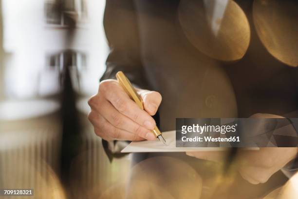 hand of businessman writing with golden fountain pen on notepad - stationery elegant stockfoto's en -beelden