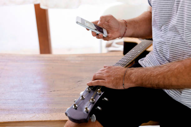 Close-up of man with guitar and cell phone