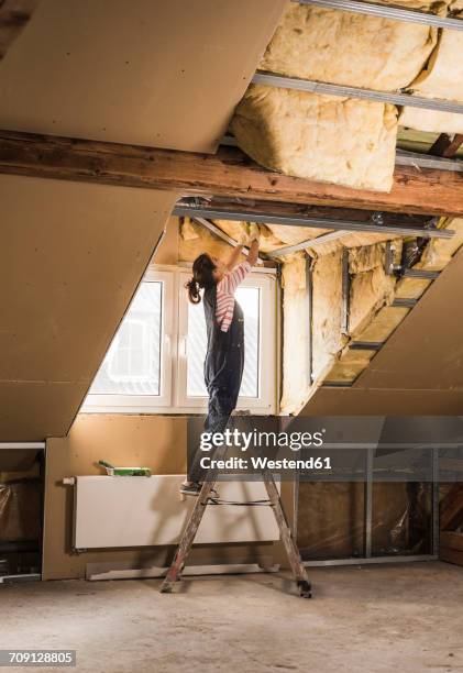 young woman mounting insulation in her new home - house insulation not posing stockfoto's en -beelden