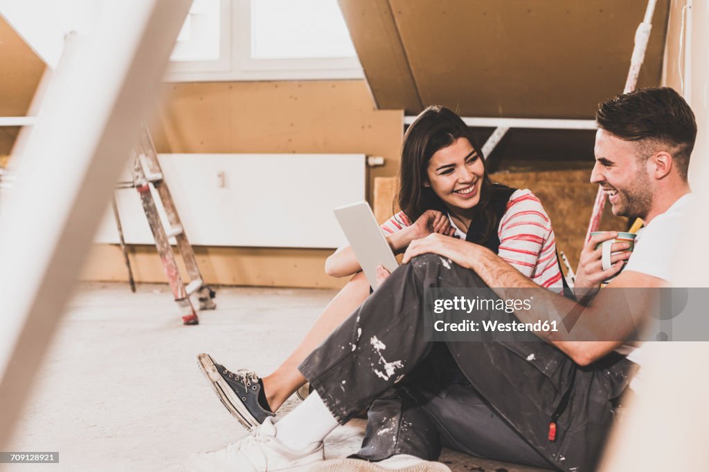 Young couple on construction site of their new home, using digital tablet