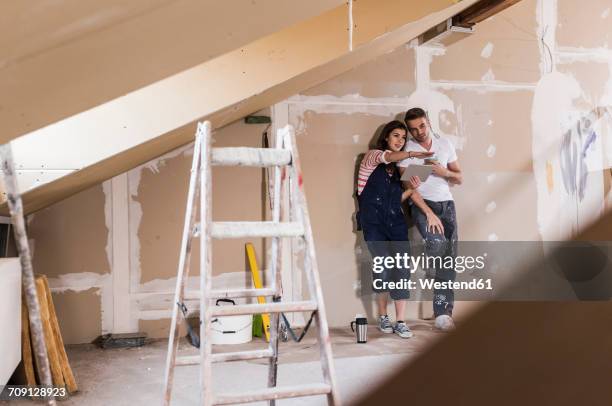 young couple on construction site of their new home, using digital tablet - rebuilding stock-fotos und bilder