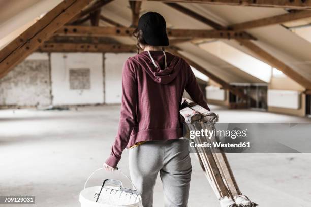 young woman on construction site carrying ladder and paint bucket - carry foundation stock-fotos und bilder
