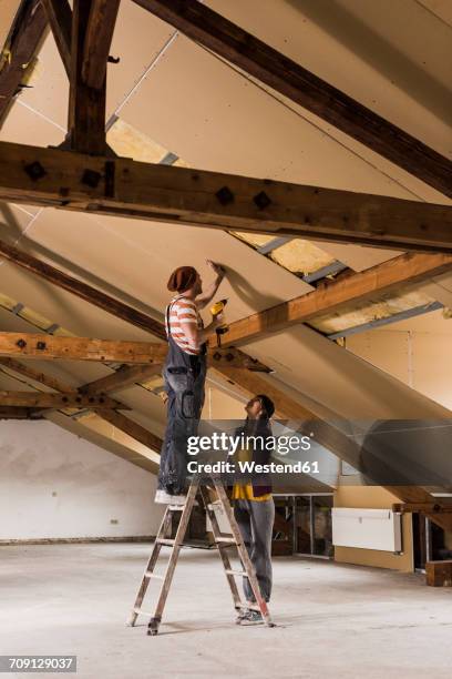 young man and woman mouting insulation on construction site - isolatiemateriaal stockfoto's en -beelden