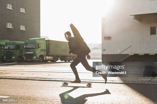 young man with guitar case riding skateboard on the street - guitar case fotografías e imágenes de stock