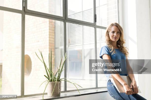 casual businesswoman in office holding folder - frau aktenordner stock-fotos und bilder