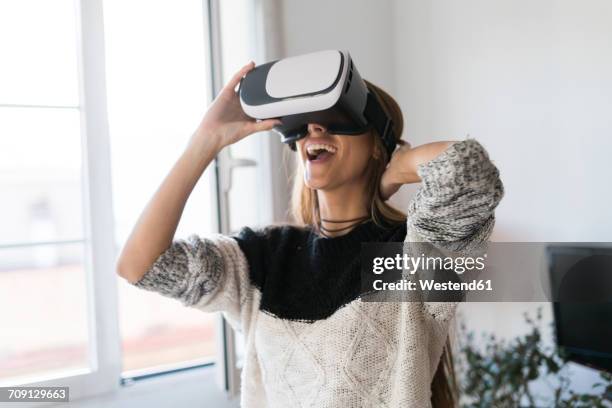 excited young woman wearing vr glasses at home - virtual fotografías e imágenes de stock